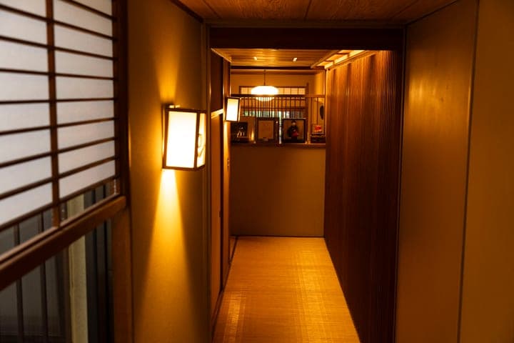 A lantern-lit wooden corridor leading into a traditional restaurant