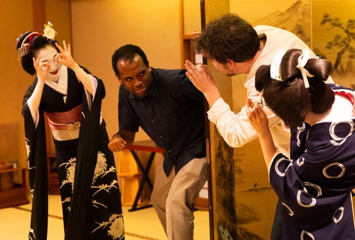 Guests and geisha laughing as they play a party game