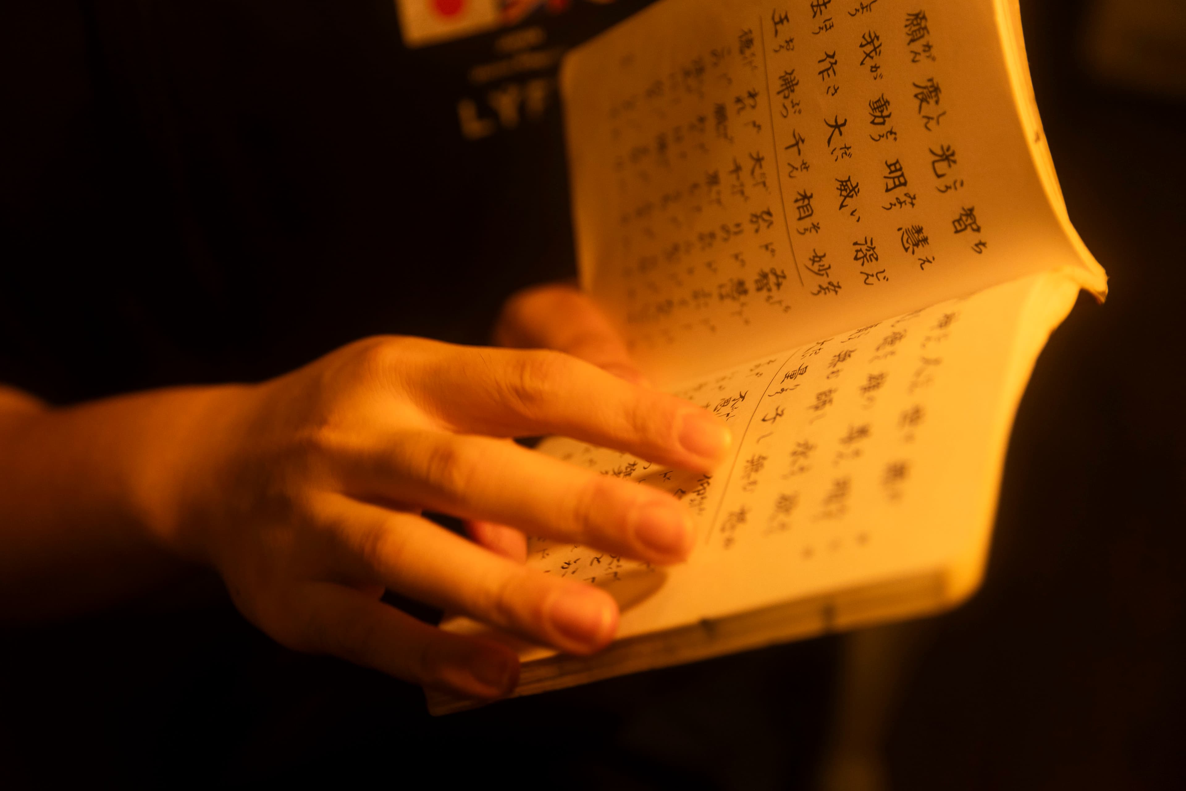 A closeup of hands turning the pages of a sutra book