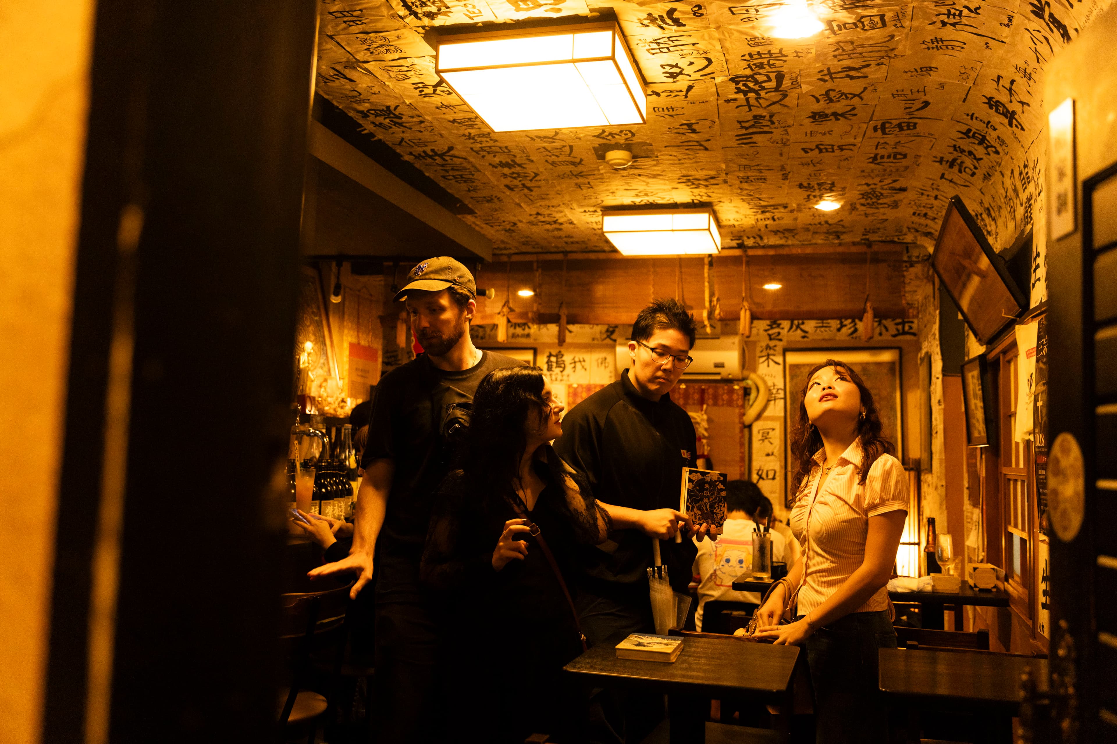 A group of people step into a bar covered in calligraphy